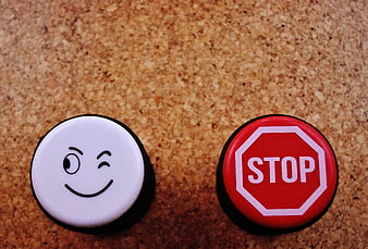 Winking smiley face and stop sign buttons on cork board
