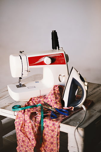 Sewing machine, iron, and fabric on rustic wooden table