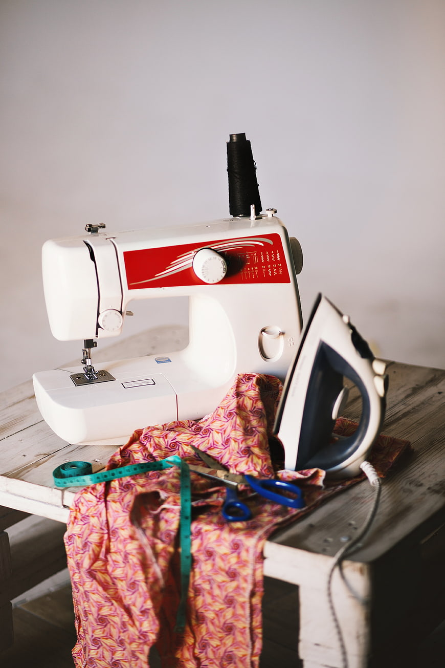 Sewing machine, iron, and fabric on rustic wooden table