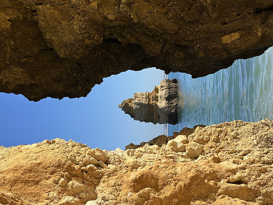 View of sea arch and rock formation from inside a cave