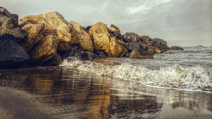 Golden Rocks on Beach with Crashing Waves and Reflections