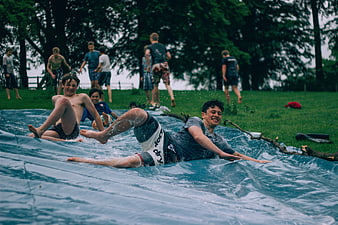 Young men sliding on a giant tarp in a park