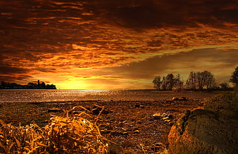 Dramatic Orange Sunset Over Lake With Distant Town Silhouette