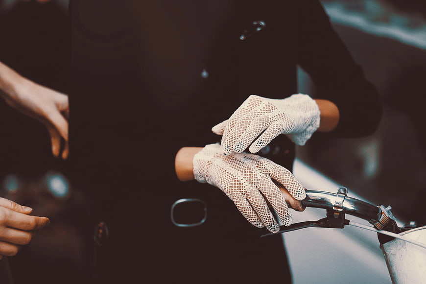 Close-up of hands in white mesh gloves on bicycle handlebars