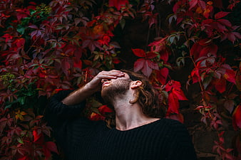 Man with hand on face against red autumn leaves