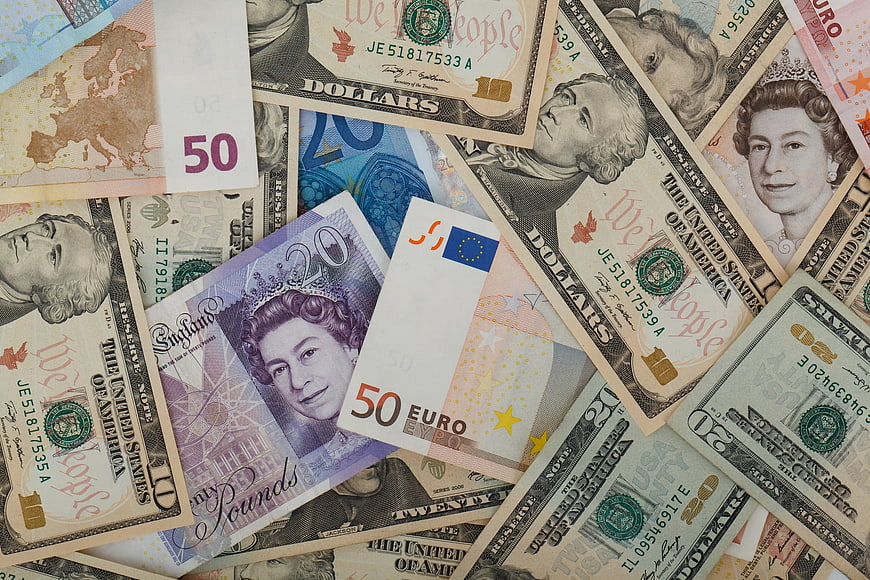 Scattered pile of international banknotes including US dollars, euros, and pounds