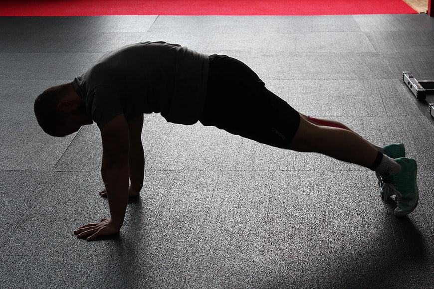 Man doing plank exercise in gym with resistance band