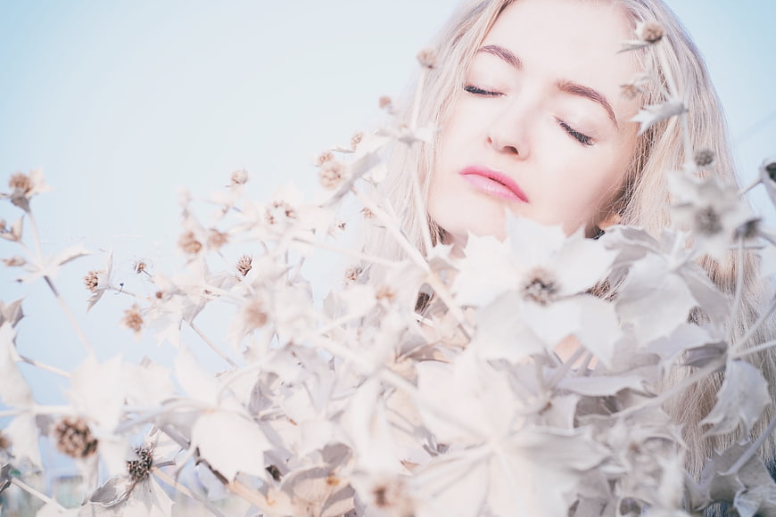 Serene blonde woman with closed eyes amidst dried flowers