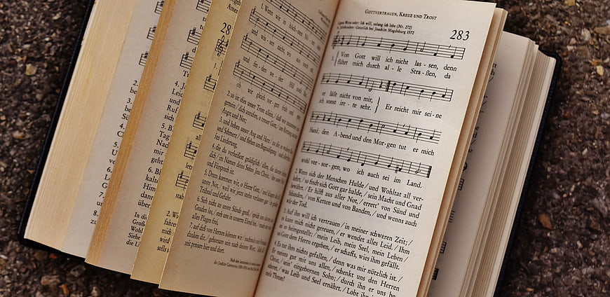 Open German Hymnal with Sheet Music on Gravel