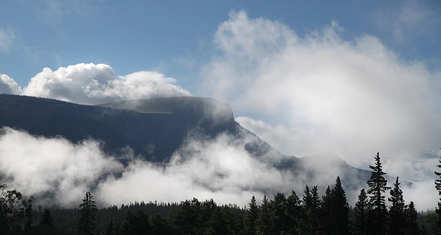 Misty Mountain Peak with Forest Silhouette and Blue Sky