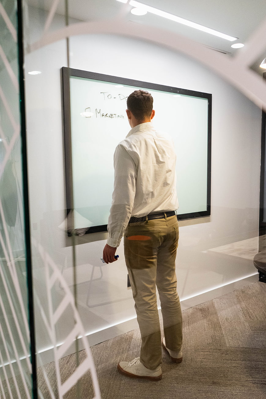 Businessman writing marketing to-do list on whiteboard