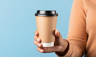Hand holding paper coffee cup on blue background