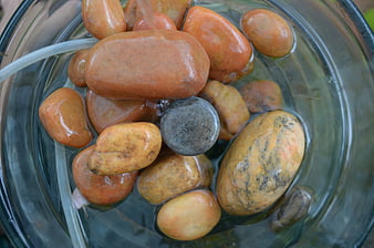 Top view of smooth orange stones in a glass water fountain