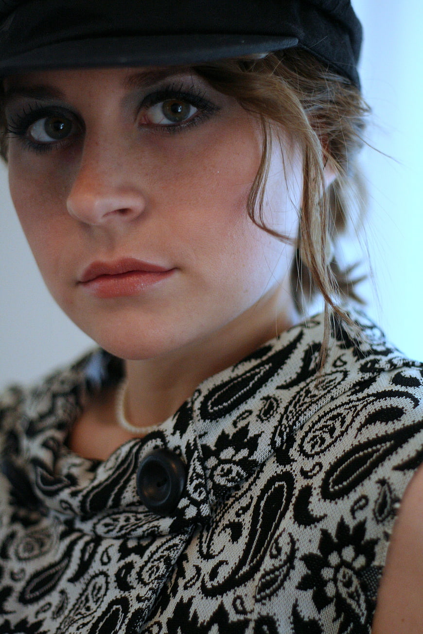 Close-up portrait of young woman in black cap and paisley top