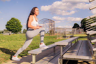 Woman stretching leg on bleachers at outdoor sports field