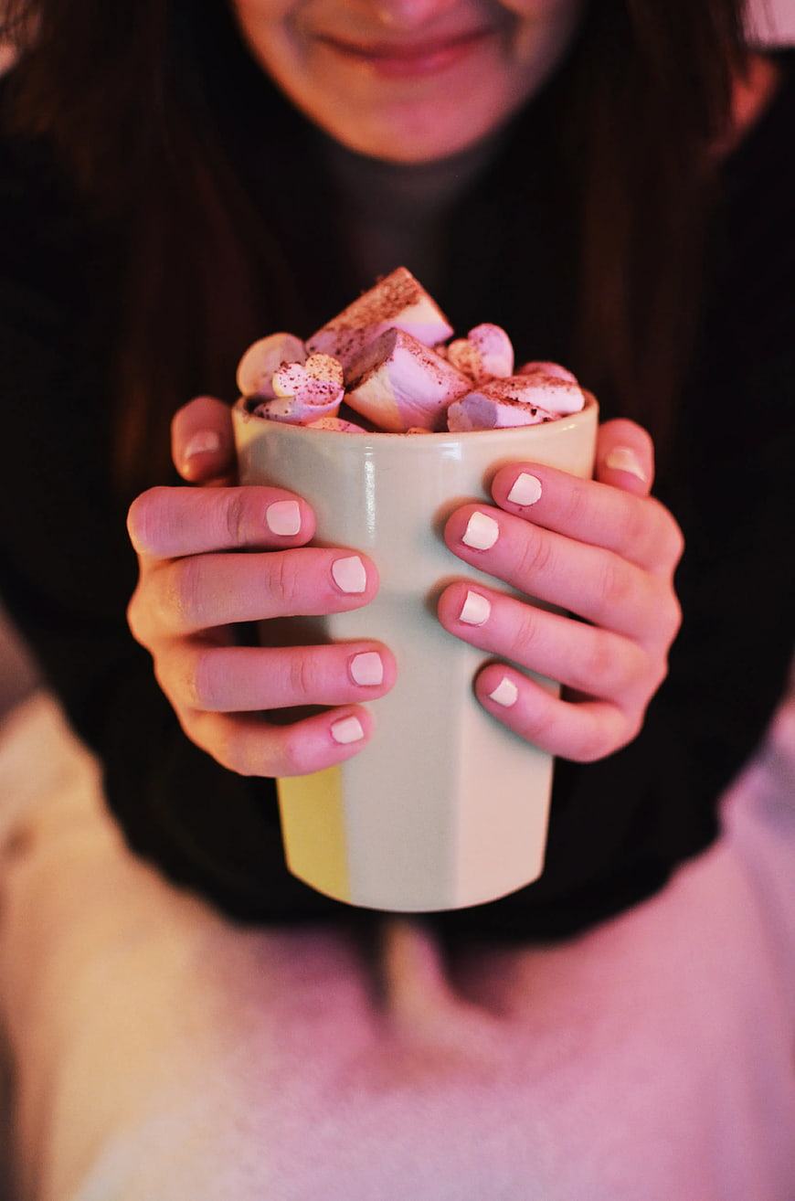 Woman holding mug of hot chocolate with marshmallows