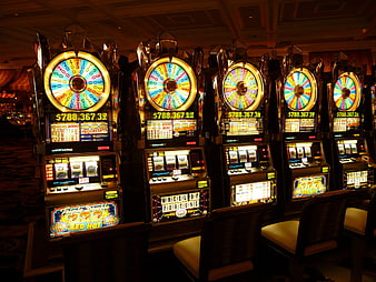 Row of illuminated slot machines in a dimly lit casino interior