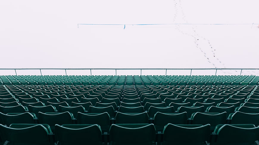 Rows of empty green stadium seats in winter snow