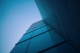 Low angle view of modern blue glass skyscraper against sky
