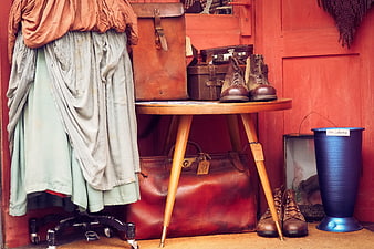 Vintage clothing, leather bags, and boots in rustic red interior