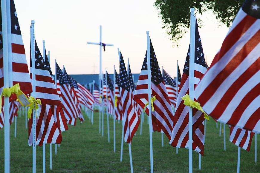 Rows of American flags with yellow ribbons at a memorial site