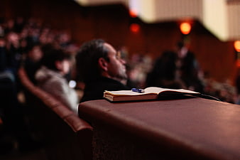Open notebook and pen on wooden desk in dark auditorium
