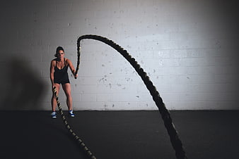 Woman Training with Battle Ropes in Gym