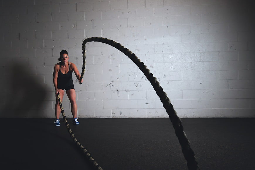 Woman Training with Battle Ropes in Gym