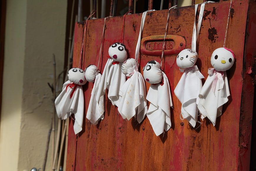 Handmade fabric dolls hanging on rustic red wooden door