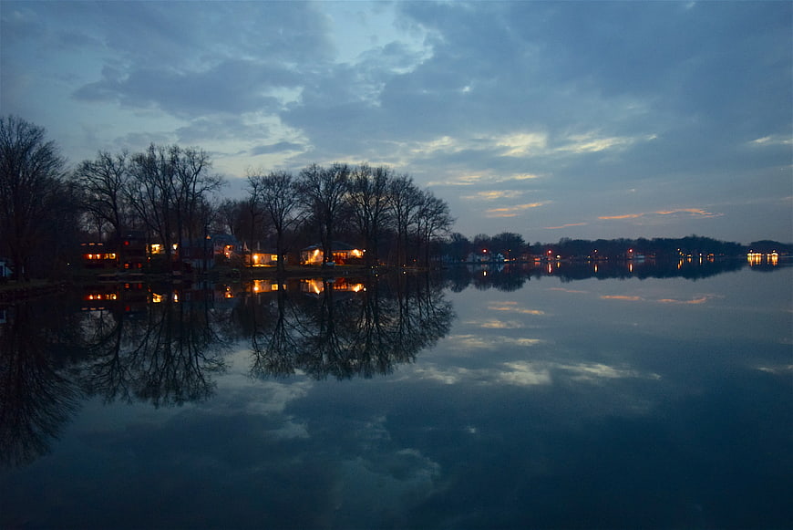Serene Lake Reflection at Dusk with Warm House Lights