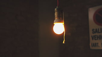 Glowing light bulb hanging in dark room with switch