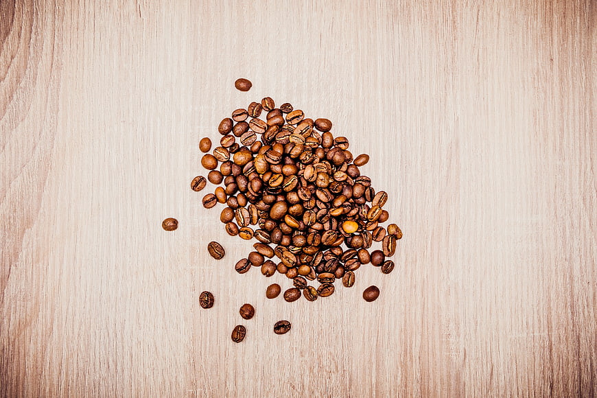 Top View of Roasted Coffee Beans on Light Wooden Table