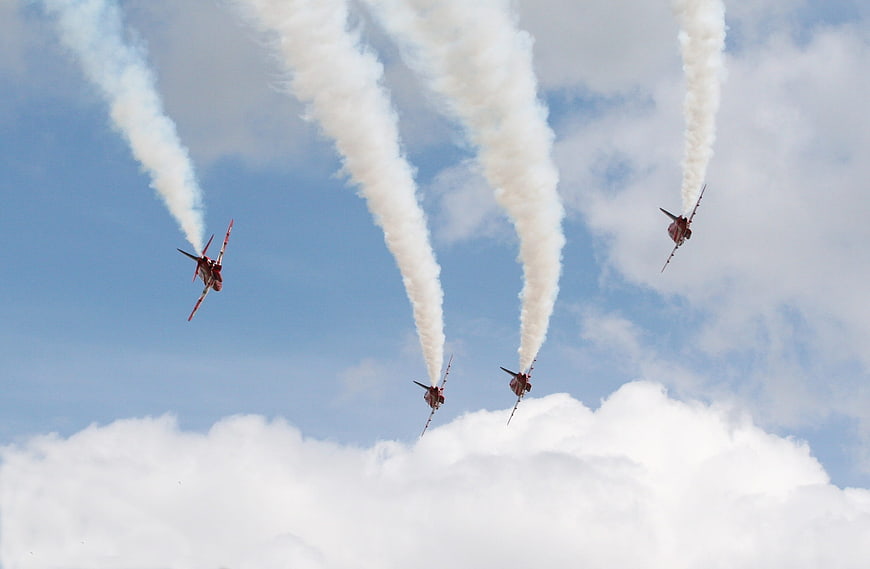 Red jets performing aerial maneuvers with smoke trails
