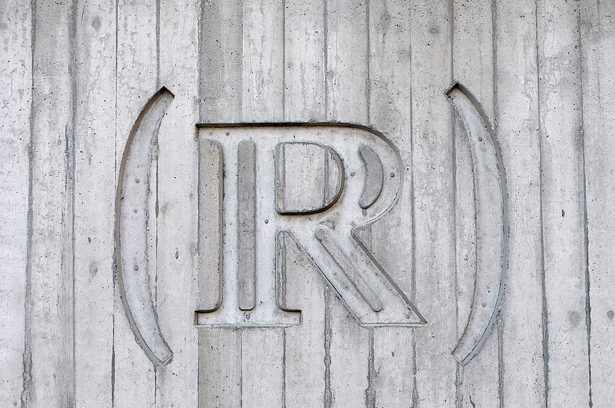 Engraved Letter R on Textured Concrete Wall