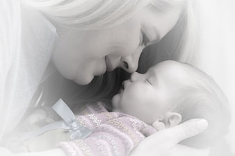 Tender black and white portrait of mother kissing newborn baby