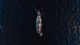 Aerial top-down view of sailboat on dark ocean water