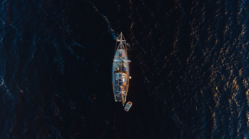 Aerial top-down view of sailboat on dark ocean water