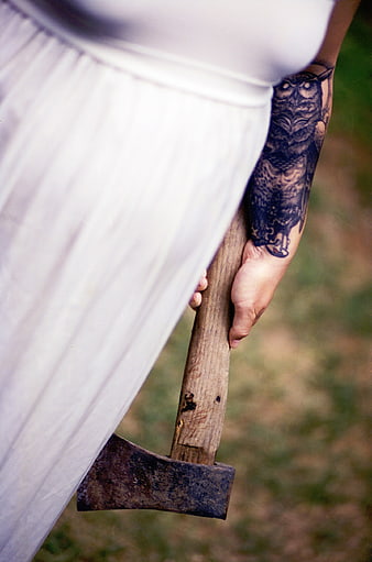 Woman with owl tattoo holding rusty axe outdoors