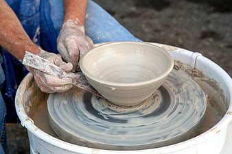 Potter shaping clay bowl on spinning wheel
