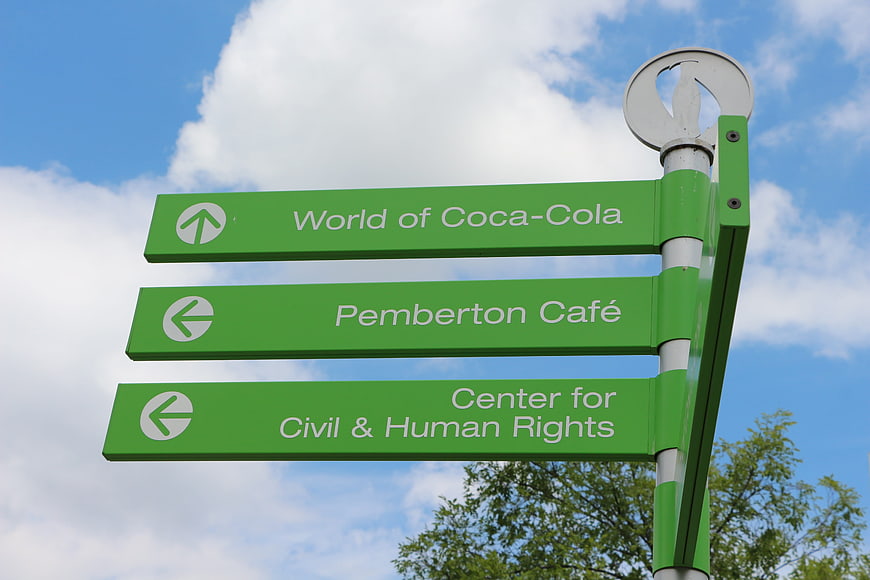 Green directional signpost for World of Coca-Cola and Pemberton Cafe