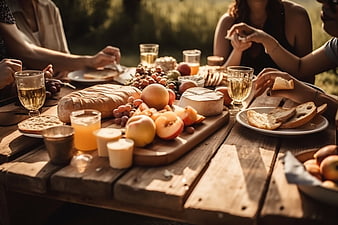 Summer picnic with bread, cheese, fruit, and wine on a wooden table