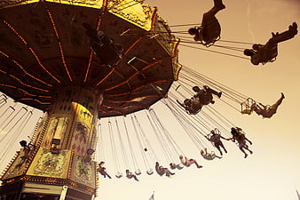 Low angle view of carnival swing ride at sunset