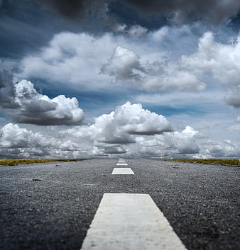 Low angle view of empty asphalt road under dramatic cloudy sky