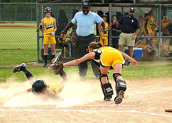 Softball player sliding into home plate with dust cloud