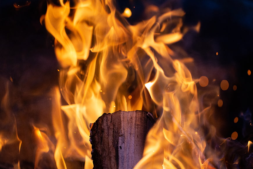 Close-up of burning wood log with bright orange flames and sparks