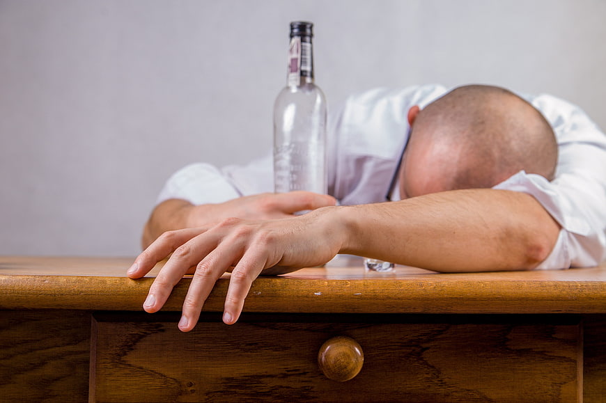 Man passed out drunk with empty bottle on table