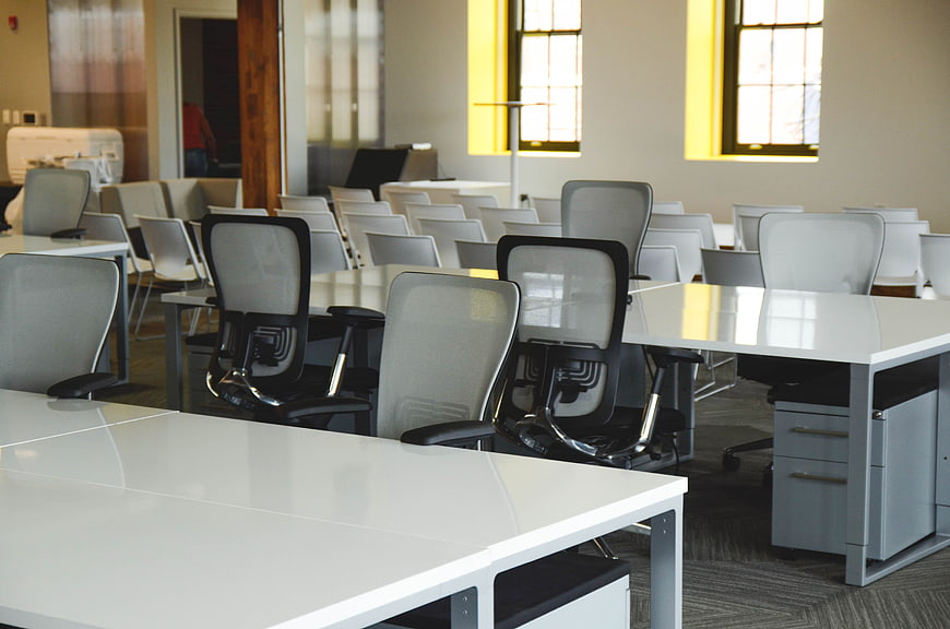 Modern empty office workspace with white desks and chairs