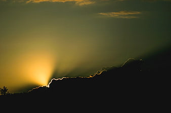 Dramatic Sunset Silhouette with Sunbeams Over Mountain Ridge