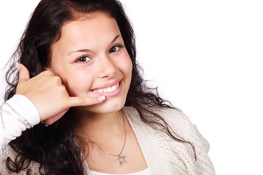 Smiling woman making call me gesture on white background