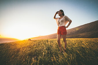 Happy woman standing in grassy field at sunset